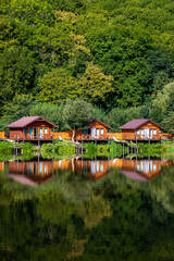 Fototapeta na wymiar Wooden houses on the water near the forest for carp fishing. A place to relax in nature. Autumn carp fishing season.