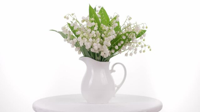 Lilies of the valley in a white vase rotate on the advertising podium. video 4k.