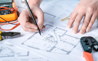 Man,repairer making electricity project in house.Repairs planning.Drawings,diagrams,plan for...