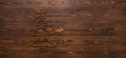 Dry food for cats or dogs in shape of Christmas tree with star on brown wooden background top view....