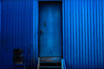 Blue metal wall. A blue metal door and a blue trash can next to it. background picture