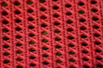 extreme close-up net texture with hexagonal holes of traditional chair seat in red plastic,...