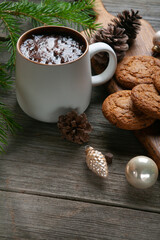 Happy New Year composition. Christmas still life made of fir branches, white cup of cocoa, oatmeal cookies with chocolate and pink toys on a rustic black wooden background