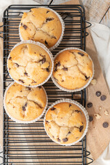 Chocolate chip muffins on a baking rack and glasses of milk on a white kitchen countertop.  Morning breakfast table. Top view, flat lay