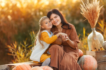 Mom and daughter at the sunset. Happy young mother hugging her daughter on sunshine warm autumn...