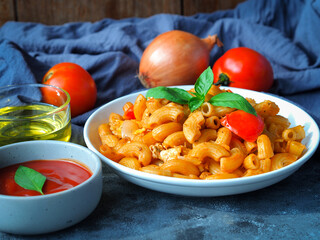 Macaroni pasta with tomato sauce in white plate on grey color table