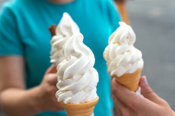 Several soft vanilla ice creams with chocolate sticks in hands