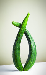 Still life of crooked fresh cucumbers. Creative still life with balancing food on a beige...
