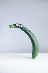 Funny long fresh cucumber with eyes . Creative still life with balancing food. Ugly vegetables.