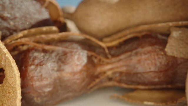 Tamarind fruits, in the shell and without, on the table, against the sky. Dolly slider extreme close-up.