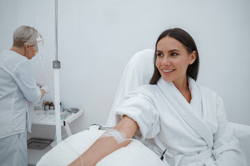 Beautiful woman in white bathrobe during medical procedure in beauty clinic