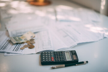 A calculator, some coins and a lot of paper utility bills on the table in close-up. No one. Place for the inscription.