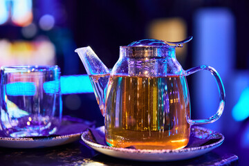 Transparent glass teapot with black tea and empty tea cup