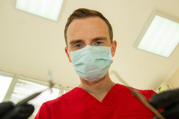 Fototapeta na wymiar doctor dentist in a red suit treats a man