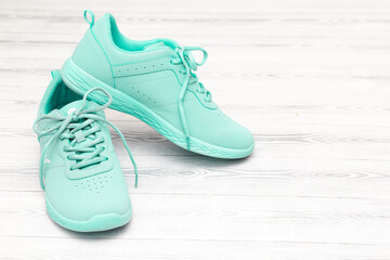 Green sneakers stand on a white wooden background. Shoes with laces top view, flat lay. The concept of sport, running and outdoor activities. Take off your shoes at home.