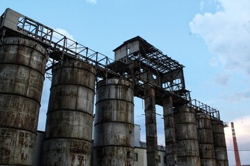 Rusty structures pipes of an old abandoned destroyed industrial steel factory. The overgrown ruins...