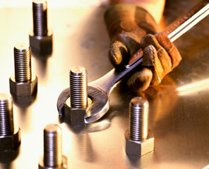 Person's gloved hand holding a spanner on a nut
