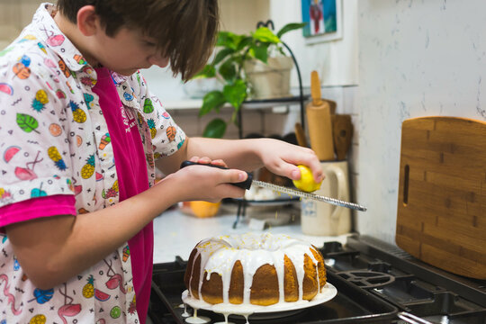 Preteen boy zests lemon on top of pound cake