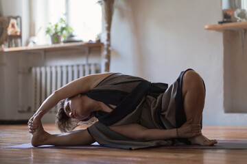 Woman practicing yoga lesson, breathing, doing twisted exercise, working out