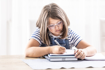 Bored girl writes homework into an exercise book