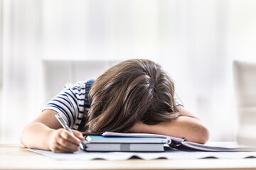 Desperate girl student has her head fallen on her arm during making homework at home