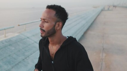 Close up, young bearded male athlete runs along the promenade - Powered by Adobe