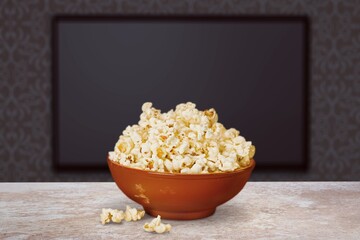 Blank tv screen behind a bowl of popcorn on the desk