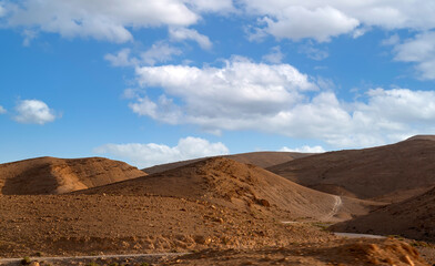 Desert at sunrise, mountain landscape with dust on skyline, hills and traces of the off-road car. a stone desert from the window of a car. Open road in desert as seen through car windscreen.