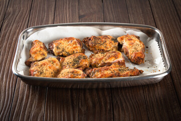 Baking pan with pieces of roasted chicken covered in cheese