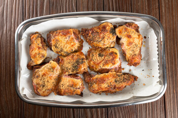 Baking pan with pieces of roasted chicken covered in cheese