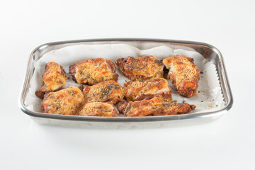 Baking pan with pieces of roasted chicken covered in cheese