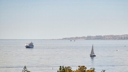 Transport ship and large luxury yacht sailing through the sea on a sunny day, off the coast of Malaga