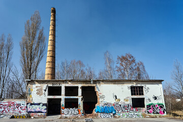 Anonymous graffiti on the walls of a ruined building and a brick chimney i