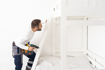 A man with instructions for assembling furniture is going to assemble in a children's bedroom