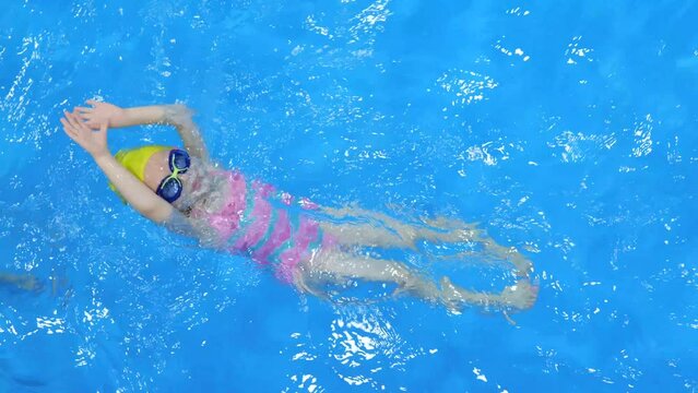 Little girl learning to swim in the pool