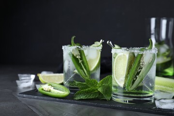 Spicy cocktail with jalapeno, cucumber and lime on black table. Space for text
