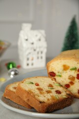 Delicious cake with candied fruits and Christmas decor on light grey table, closeup