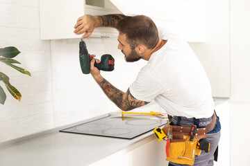 Male Worker Fixing Kitchen Hood With Screwdriver In Kitchen - Powered by Adobe