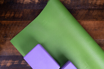 Yoga mat and blocks on a wooden floor.  Copy space.