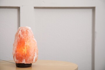 Himalayan salt lamp on wooden table indoors. Space for text