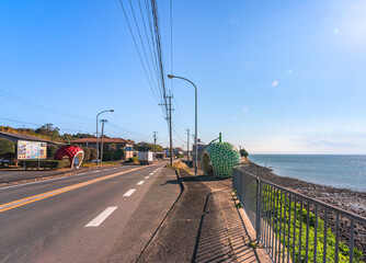 kyushu, japan - december 10 2021: Highway 207 of Isahaya city along ariake sea which Hirahara bus stops shaped as giant strawberry and cantaloupe fruits are part of Tokimeki Fruit-shaped Avenue.
