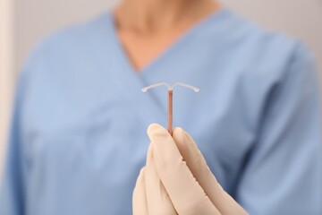 Doctor holding T-shaped intrauterine birth control device, closeup