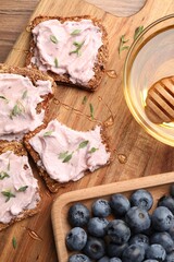 Tasty sandwiches with cream cheese, honey and thyme on wooden table, flat lay