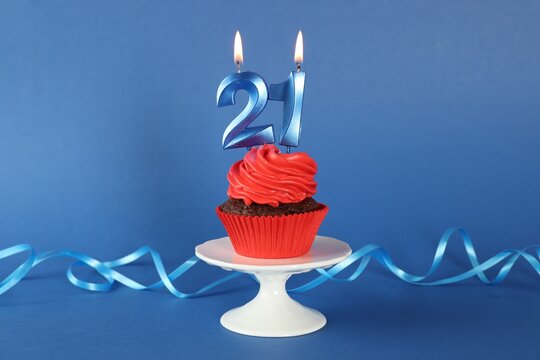 Delicious cupcake with number shaped candles on blue background. Coming of age party - 21th birthday