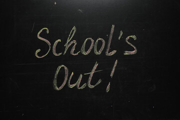 Text SCHOOL'S OUT written on blackboard. Summer holidays