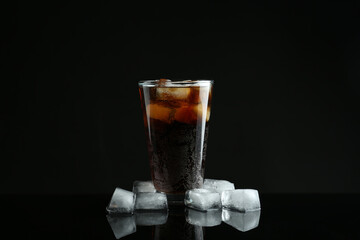 Glass of refreshing soda water with ice cubes on black background