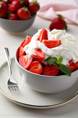 Delicious strawberries with whipped cream served on white wooden table