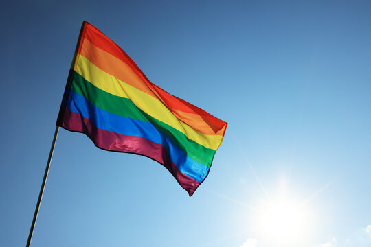 Bright LGBT flag fluttering against blue sky