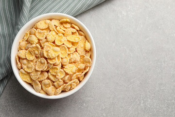 Bowl of tasty corn flakes on light grey background, top view. Space for text