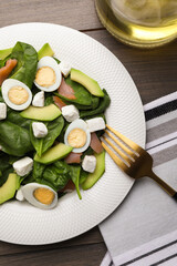 Delicious salad with boiled eggs, feta cheese and salmon served on wooden table, flat lay